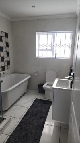 a bathroom with a tub sink and a toilet at Sixty On Whales in Gqeberha