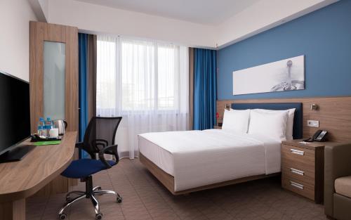 a hotel room with a bed and a desk and a computer at Hampton By Hilton Astana Triumphal Arch in Astana