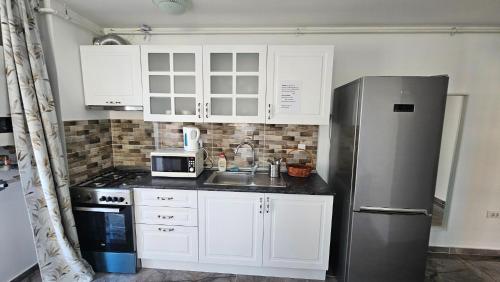a kitchen with white cabinets and a stainless steel refrigerator at Airport Residence in Otopeni
