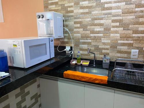 a kitchen counter with a microwave and a sink at Casa Maria Alice in Manhã