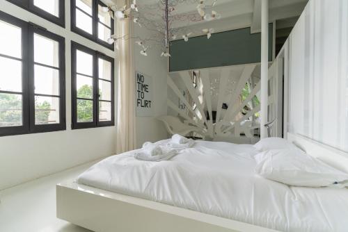 un lit blanc dans une chambre avec des fenêtres dans l'établissement Demeure Historique et Artistique à Amboise avec Piscine, à Nazelles-Négron