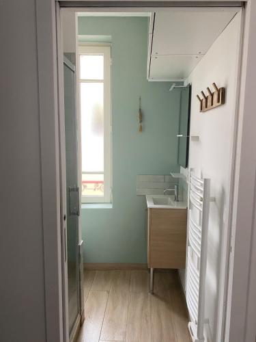 une salle de bain avec un lavabo et une fenêtre dans l'établissement La tranquillité trouvillaise, à Trouville-sur-Mer