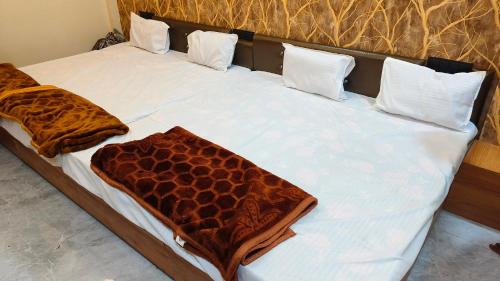 a bed with brown and white sheets and pillows at Hotel Naagshree in Ujjain