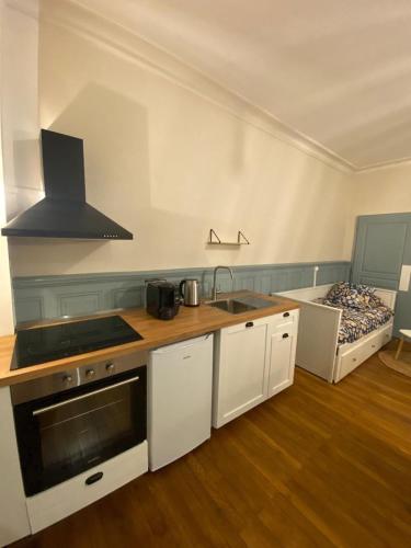 une cuisine avec des armoires blanches et un évier et un lit dans l'établissement L'Imprimerie A1, studio cosy au cœur de la Roche !, à La Roche-sur-Yon