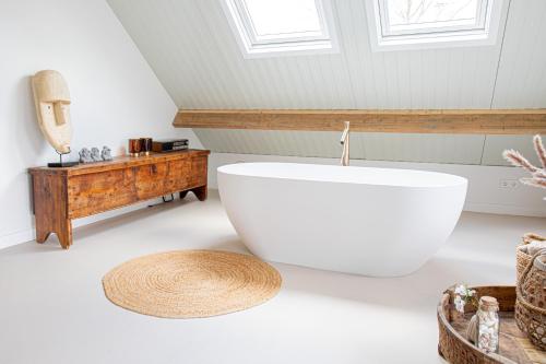 a bathroom with a large white tub in a room at By Tons Huisje inclusief twee fietsen in Zegveld