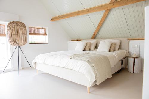 a white bedroom with a large bed with white sheets at By Tons Huisje inclusief twee fietsen in Zegveld