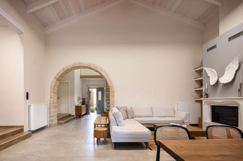 a living room with a white couch and a fireplace at Artemis Apollonas Villa I Luxury Escape with Pool in Káïna