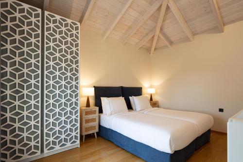 a bedroom with a large white bed and a wall at Artemis Apollonas Villa I Luxury Escape with Pool in Káïna