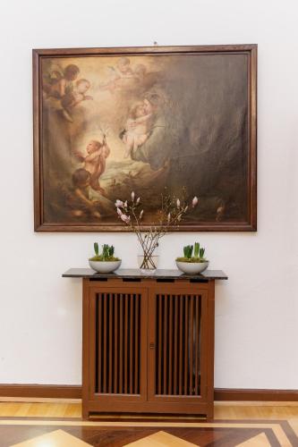 a painting hanging on a wall with a table with flowers at Hotel Schloss Höhnscheid in Bad Arolsen