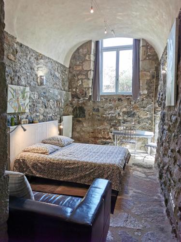 - une chambre avec un lit et un canapé dans un mur en pierre dans l'établissement Le CLOS MARFRUMA, à Montréal