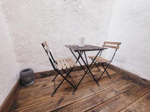 une table et deux chaises assises à côté d'un mur dans l'établissement Mahé , appartement Intramuros, à Avignon