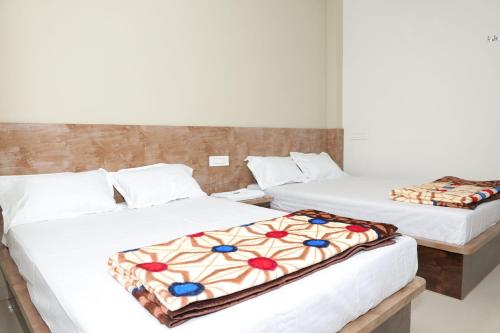 two beds in a room with white sheets at Shree Jyotirlinga Residency in Ellora