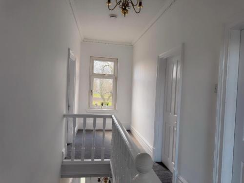 a white hallway with a staircase and a window at Double-Bedroom in the Heart of Salford Manchester GCSW1 Perfect for Short Stays in Manchester