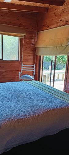 a bedroom with a bed in a log cabin at Refugio Silvestre Parque Nacional Siete Tazas-Salida a río y pesca in El Bolsico