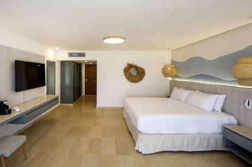 a bedroom with a white bed and a television at Viva Miches by Wyndham, a Trademark All Inclusive Resort in Miches
