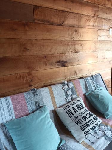 a bed with two pillows and a wooden wall at Refugio Silvestre Parque Nacional Siete Tazas-Salida a río y pesca in El Bolsico