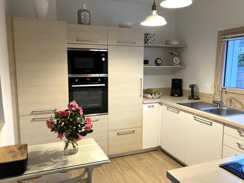 une cuisine avec un vase de fleurs sur une table dans l'établissement Maison avec jardin, terrasse, WIFI au centre de PERROS-GUIREC - Réf 949, à Perros-Guirec