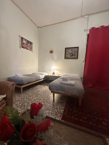 two beds in a room with red curtains and roses at Rosa apartment in Venice