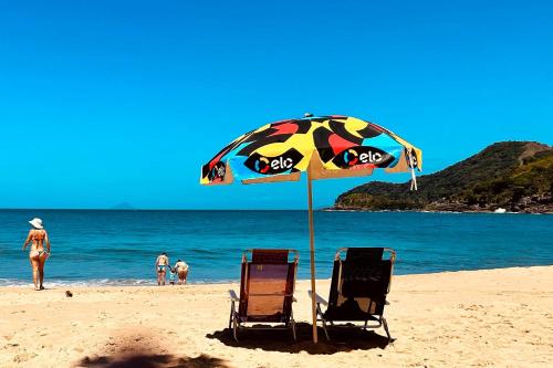 zwei Stühle und ein Sonnenschirm am Strand in der Unterkunft 300m da praia, AC, churrasqueira| Brazilian Corner in Toque Toque Grande