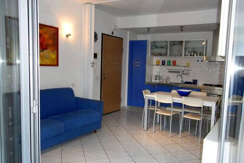 a living room with a blue couch and a kitchen at Appartamento Blu in Giulianova