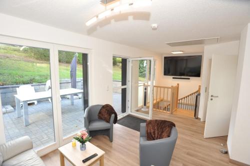 ein Wohnzimmer mit einem Sofa, Stühlen und einem TV in der Unterkunft Ferienhaus Fuchswinkel in Güntersberge
