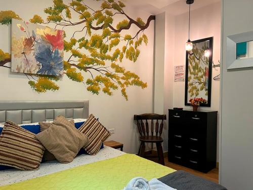 a bedroom with a bed with a tree on the wall at Hotel Boutique Stay La 10 in Medellín