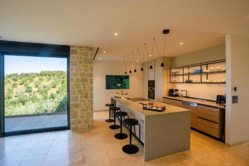 a kitchen with a large window and a counter with stools at Messinian Nest in Gialova