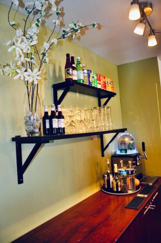 a bar with a shelf on the wall with bottles and glasses at Kyriad Toulouse Sud - Roques in Roques Sur Garonne