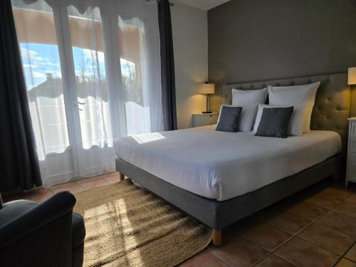 a bedroom with a large bed and a large window at Hôtel Le SAINT-GENIÈS in Uzès