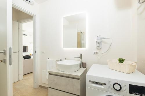 a white bathroom with a sink and a mirror at Navarra Beach House in Santa Maria Navarrese