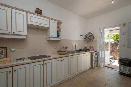 a kitchen with white cabinets and an open door at Villa La HOULE- beachfront,private pool,3 bedrooms in Cap Malheureux