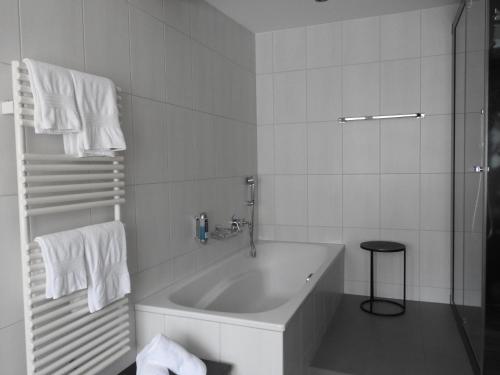 a white bathroom with a tub and a stool at Hotel Spöl Restaurant in Zernez