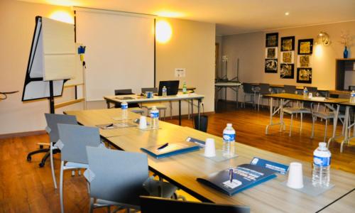a conference room with tables and chairs and a screen at Kyriad Toulouse Sud - Roques in Roques Sur Garonne
