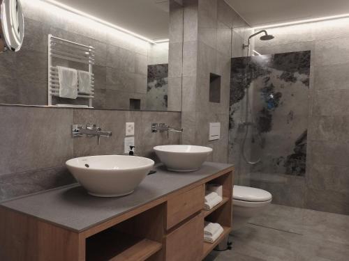 a bathroom with two sinks and a toilet at Hotel Spöl Restaurant in Zernez