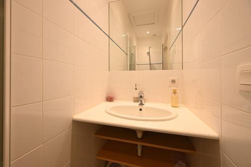 ein weißes Badezimmer mit Waschbecken und Spiegel in der Unterkunft Villa Coraly - piscine chauffée et jardin in Sainte-Marie-de-Ré