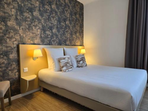 a bedroom with a bed with two pillows on it at Hôtel Le SAINT-GENIÈS in Uzès