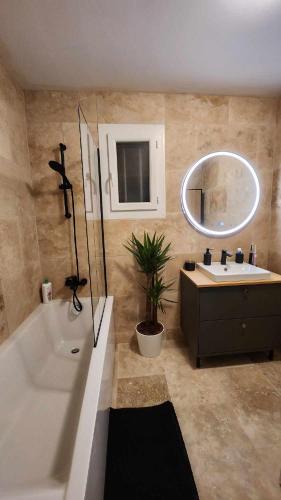 une salle de bain avec une baignoire, un lavabo et un miroir dans l'établissement Chez Camille, à Cuges-les-Pins