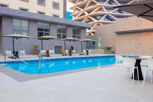 a swimming pool with tables and chairs and umbrellas at Palms by Eagles Airport City, Formerly Holiday Inn in Accra