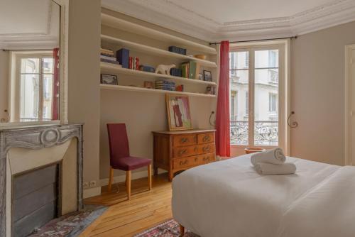 - une chambre avec un lit, une cheminée et une chaise dans l'établissement Paris Courcelles Prestige Residence, à Paris