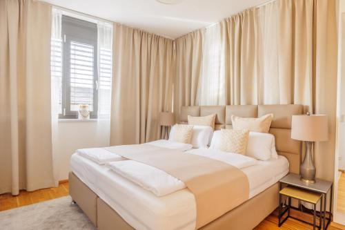 a bedroom with a large white bed with a window at Luxury Apartment Villach City in Villach