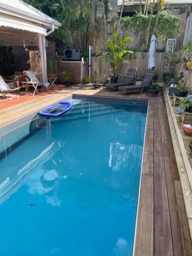 a swimming pool in a backyard with a wooden deck at Casefilo in Sainte-Luce