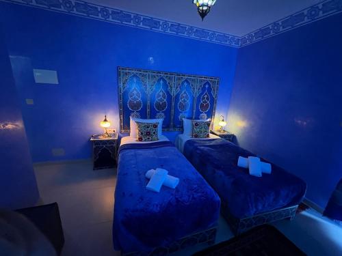 two beds in a blue room with blue walls at Puerta Azul in Chefchaouene