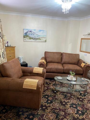 a living room with two brown couches and a table at Barons Court in Great Yarmouth