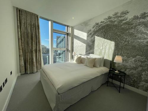 a bedroom with a large bed and a large window at Battersea Power Apartments in London