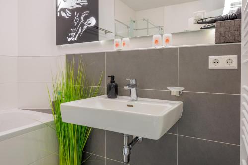 a white sink in a bathroom with a green plant at Luxury Apartment Villach City in Villach
