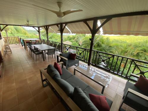 a living room with a couch and tables and a balcony at Colibri Villa Sainte Luce in Sainte-Luce