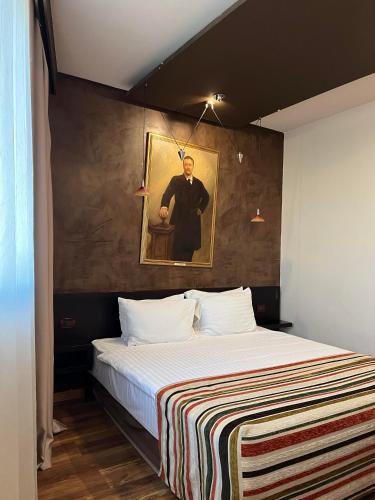 a bedroom with a bed with a painting of a man at Design Hotel Mr President in Belgrade