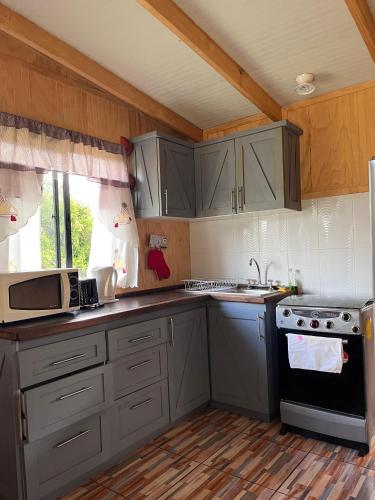 a kitchen with gray cabinets and a stove at Cabaña playa Chauquen, Panguipulli in Panguipulli