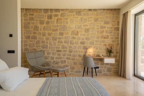 a bedroom with a brick wall and two chairs and a bed at Messinian Nest in Gialova
