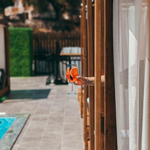 a person holding a wine glass leaning out of a window at Bianco Hotel in Ksamil
